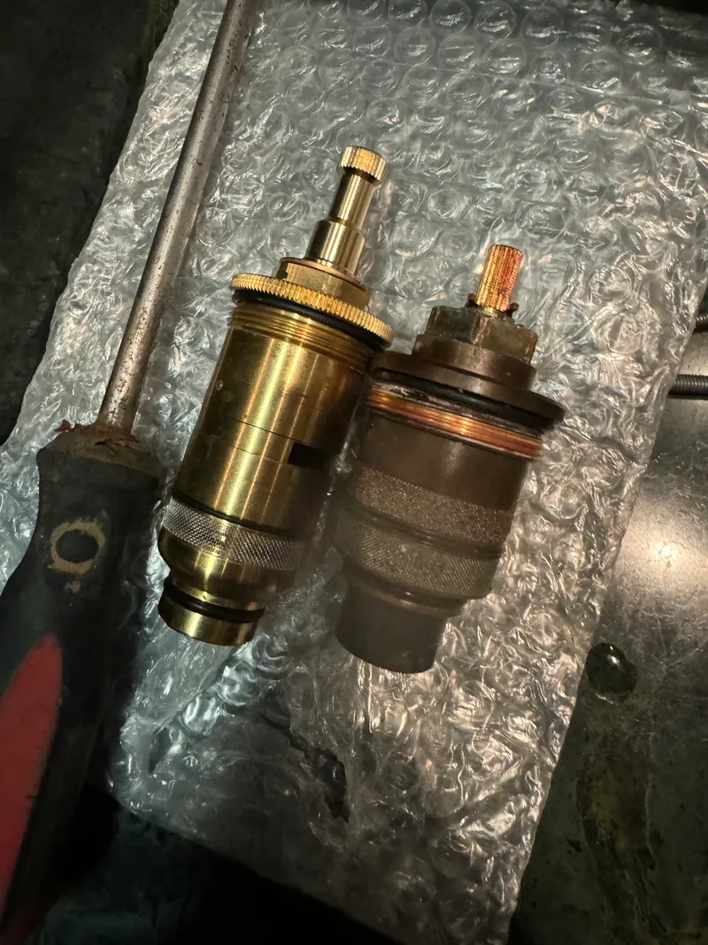 Side-by-side comparison of worn and new brass shower valve cartridges