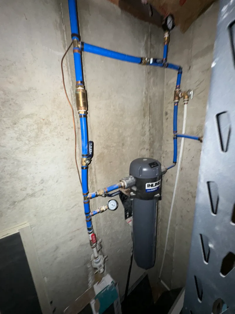 Water filtration system with blue PEX supply lines and brass valves